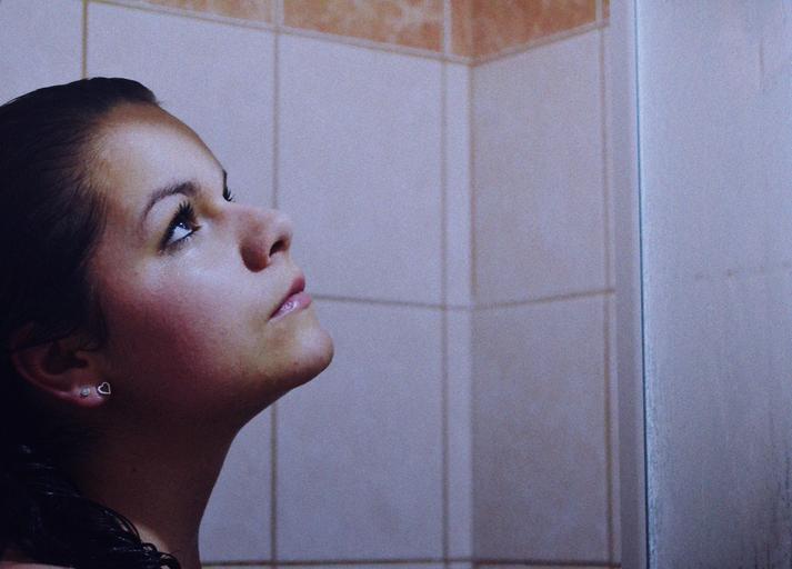Žena s čiernymi vlasmi stojí v sprchovom kúte